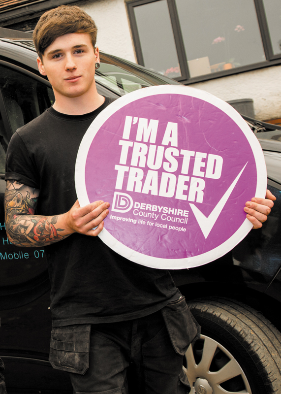 Billy Hewitt proudly holding the Derbsyhire Trusted Trader logo board